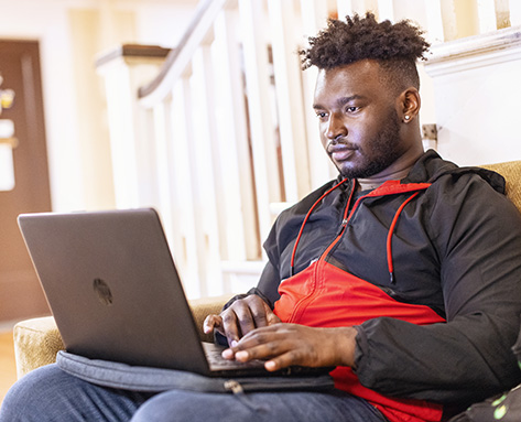 a student working on his laptop in an academic building