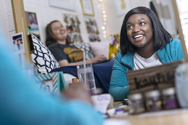a student laughing with her roommate in their dorm room