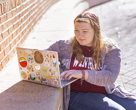 a student working outside on a laptop