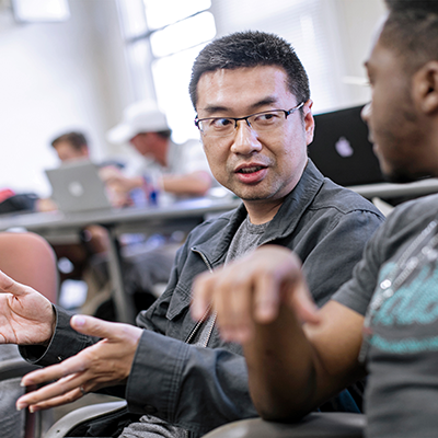 Two men talking in what looks like a computer lab
