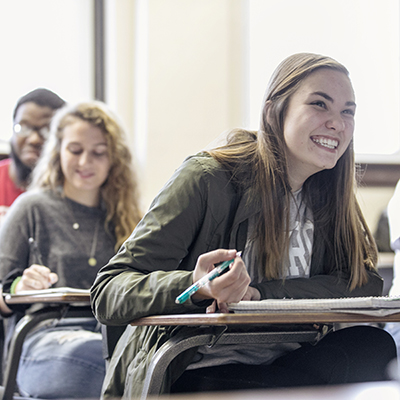 Woman laughing while sitting in a desk in a classroom