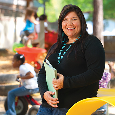 Woman standing in a playground holding file folders