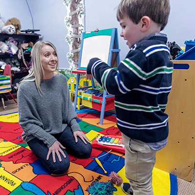 Woman in a classroom-like setting talking to a small boy