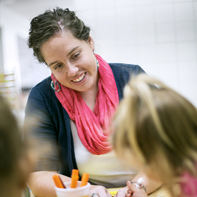 Woman sitting at a table with kids that are coloring