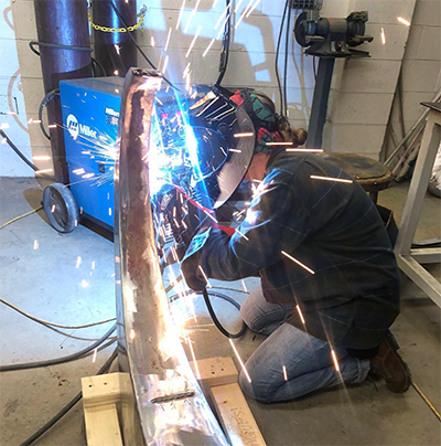 A person welding a curved sculpture