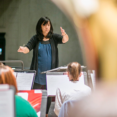 Woman conducting a group of students from across the room