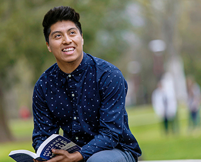 a student sitting outside and holding a book
