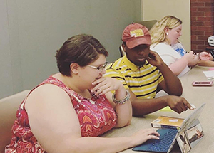 A tutor works with a student on a laptop.